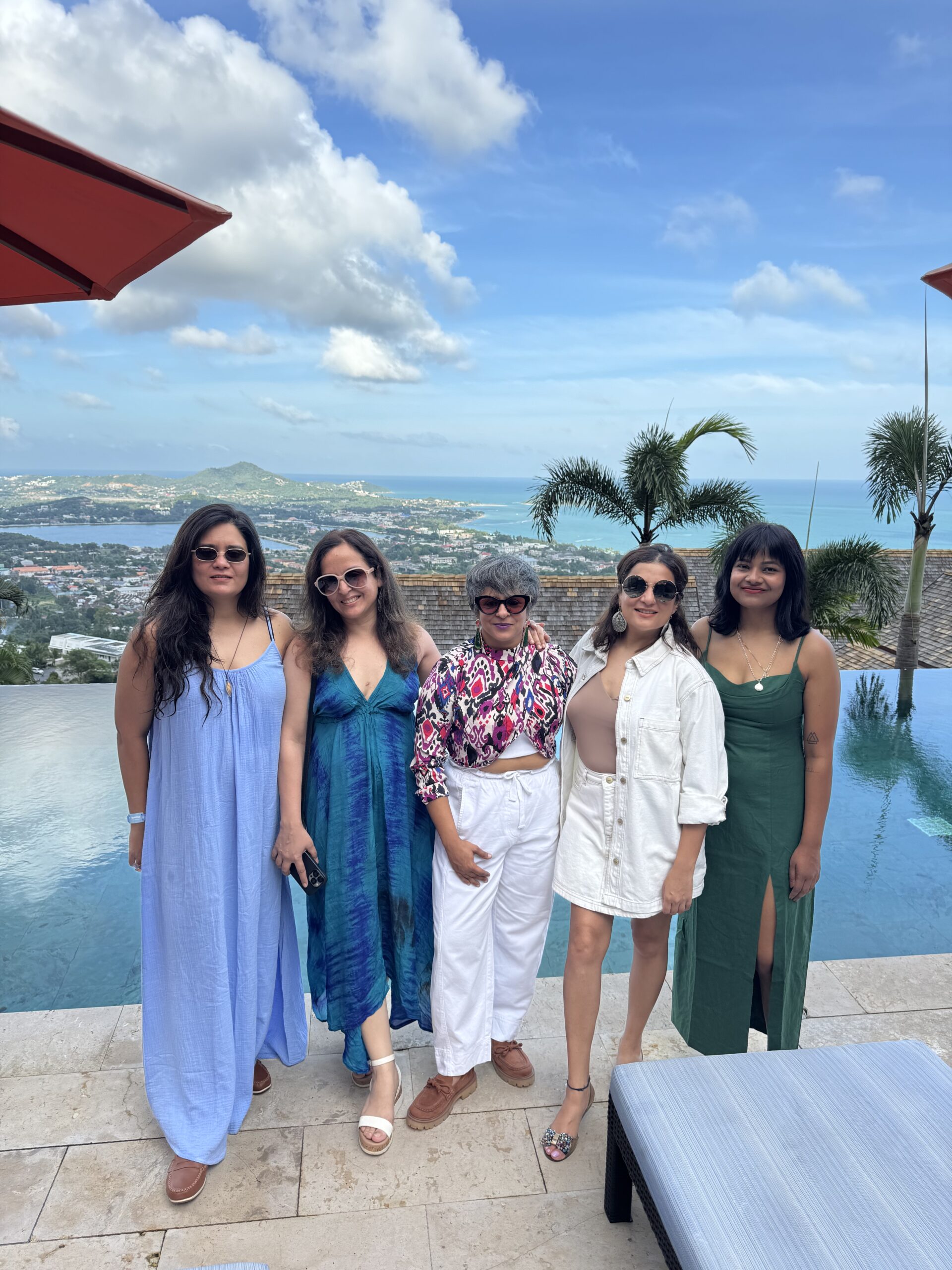 Group of women friends on a group travel trip by an infinity pool